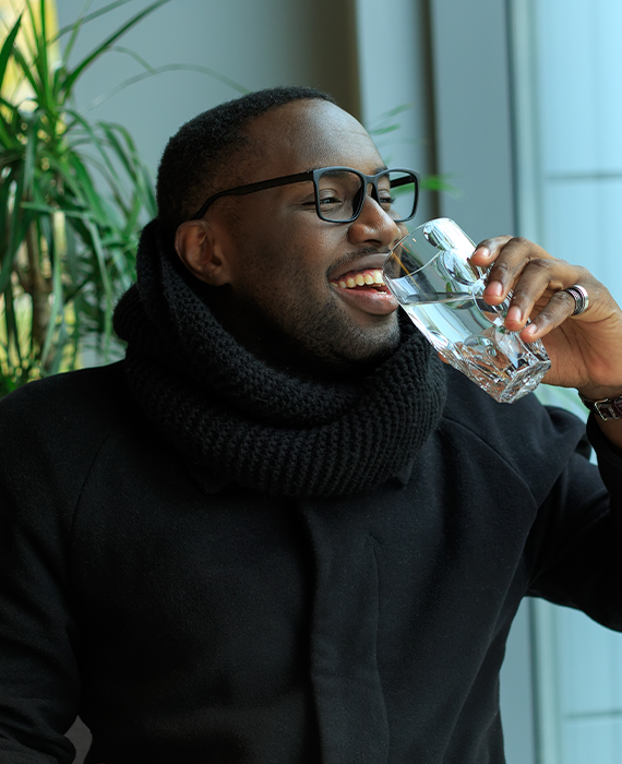 Photo of smiling man drinking a glass of water.