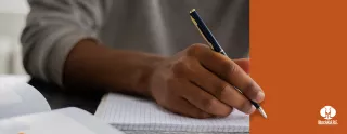 Image of a hand holding a pen, hovered over a blank notebook