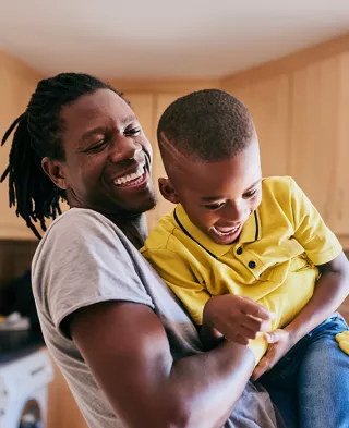 Photo of a smiling father holding his son