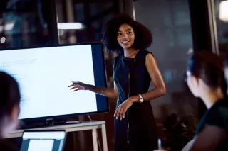 Photo of a woman demonstrating a screen presentation to an audience